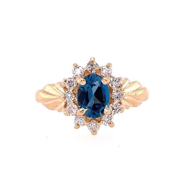 Lady's Yellow 14 Karat Princess Di Fashion Ring Size 7 With One 0.80Ct Oval Blue Blue Topaz And 12=0.60Tw Round G/H Vs2- Si1 Diamonds